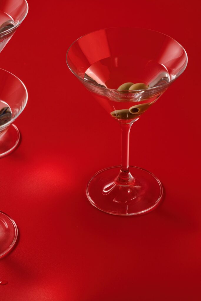 a red table topped with two wine glasses filled with olives