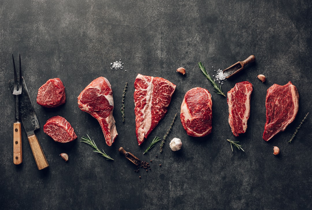 raw meat on a table with a knife, garlic and pepper
